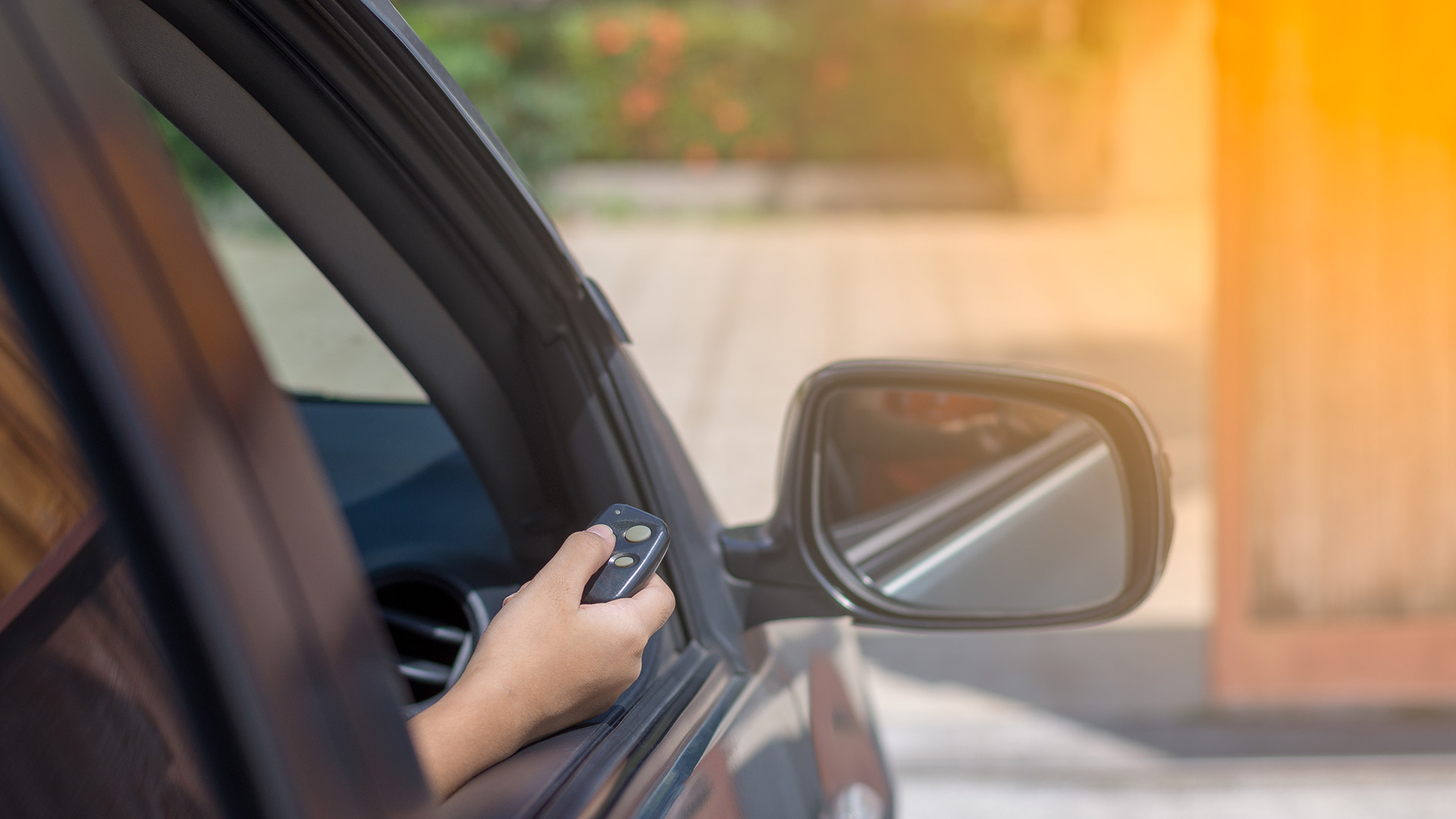 hand out car window holding garage door remote