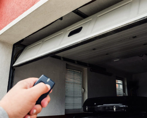 person pointing at garage door opener with remote