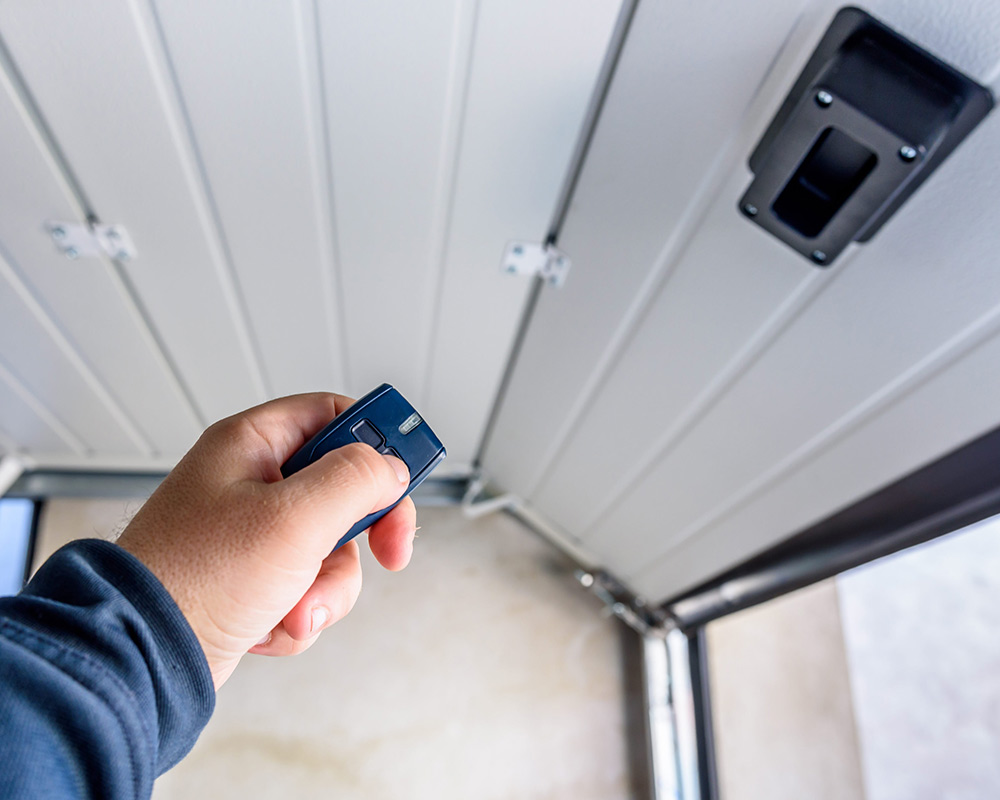 persons hand with remote opening garage from inside